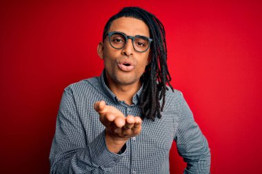 Rastgele gömlek giyen ve gözlüklü genç, Afro-Amerikan adam kameraya bakıp havada öpücükler savuruyor. Güzel ve seksi. Aşk ifadesi.