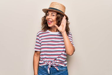 Orta yaşlı, çizgili tişört ve şapkalı güzel bir kadın izole edilmiş beyaz arka planda sırıtarak dedikodu ya da dedikoduları dinliyor. Sağırlık kavramı.