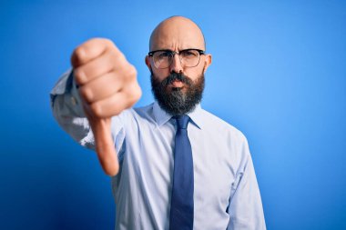 Yakışıklı, kel, sakallı, zarif kravat takan, mavi arka planda gözlük takan, mutsuz, sinirli, reddedilmiş ve olumsuz görünümlü bir adam. Kötü ifade.