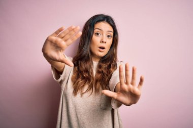 Genç, güzel, esmer bir kadın pembe arka planda dikiliyor. Avuç içi hareketlerini durduruyor. Öfkeli ve hüsran dolu bir ifade takınıyor.