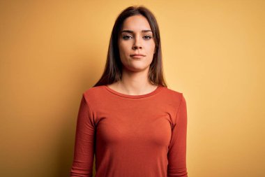 Genç, güzel, esmer, günlük tişört giyen, sarı arka planda duran, uykulu ve yorgun görünen, yorgunluktan bitkin ve akşamdan kalma, tembel gözlü kadın..