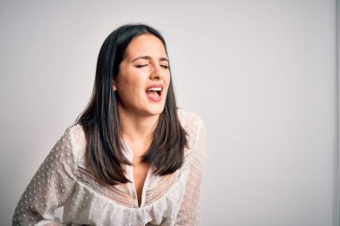 Mavi gözlü genç esmer kadın izole edilmiş beyaz arka plan üzerine gündelik tişört giyiyor. Midesi bulanıyor ve acı çekiyor. Ache kavramı.