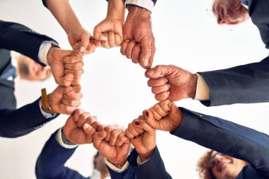 Group of business workers smiling happy and confident. Standing on a circle with smile on face doing symbol with fists together at the office.