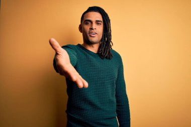 Sarışın, yeşil kazaklı, yakışıklı Afro Amerikalı genç adam dostça bir selamlama ve hoş geldin hediyesi olarak gülümsüyor. Başarılı bir iş..