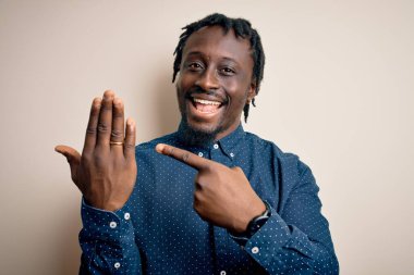 Genç Afrikalı Amerikalı adam, altın evlilik yüzüğünü beyaz arka planda parmağında gösteriyor.