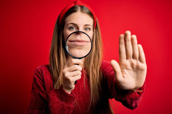 Joven Hermosa Mujer Detective Pelirroja Utilizando Lupa Sobre Fondo Rojo —  Fotos de Stock