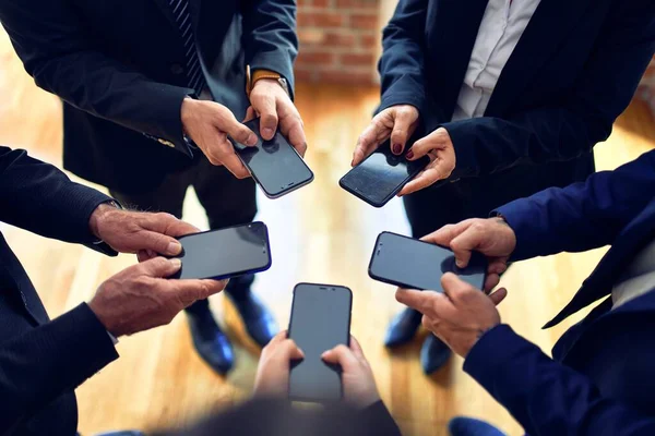 Group of business workers standing on a circle using smartphone together at the office.