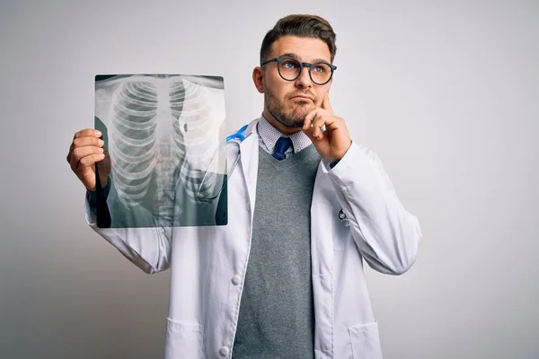 身穿医疗外套的年轻医生用胸部X光透视孤立的背景严肃地思考问题 非常混乱的想法 — 图库照片