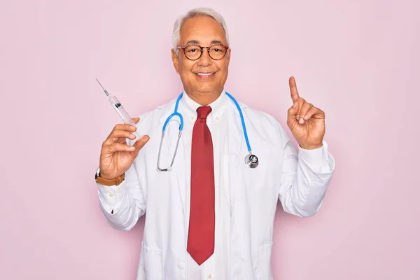 中年シニア白髪医師男保持医学針注射以上ピンクの背景驚きでアイデアや質問を指差す指で幸せな顔 ナンバーワン — ストック写真