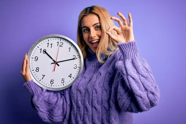 Young Beautiful Blonde Woman Doing Countdown Holding Big Clock Purple — Stock Photo, Image