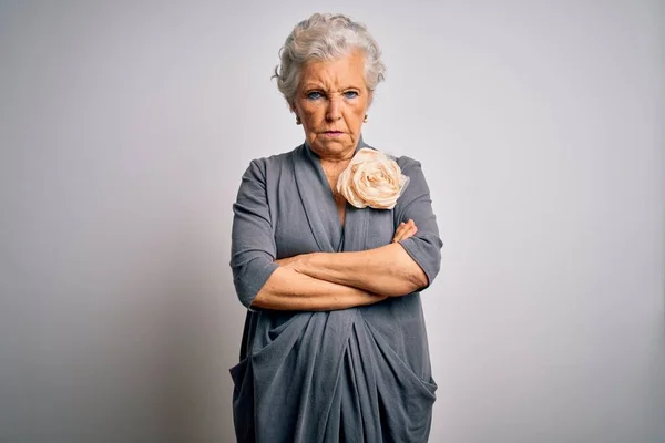 Senior beautiful grey-haired woman wearing casual dress standing over white background skeptic and nervous, disapproving expression on face with crossed arms. Negative person.