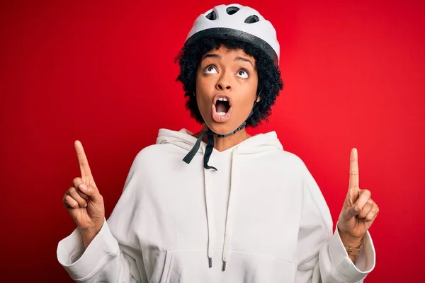 年轻的非洲裔美国人骑自行车的女人 卷曲的头发 戴着自行车安全帽 惊讶地抬起头 用手指和胳膊指指着 — 图库照片