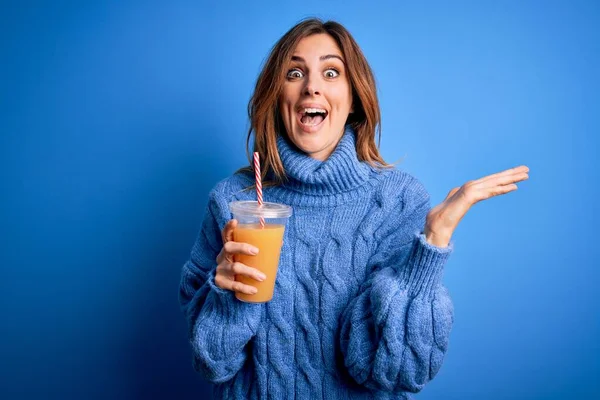 Young Beautiful Brunette Woman Drinking Healthy Orange Juice Blue Background — Stock Photo, Image