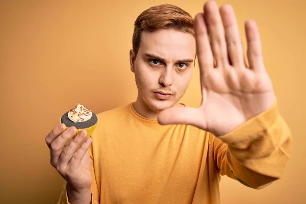 Young Handsome Redhead Man Eating Sweet Chocolate Cupcake Dessert Yellow — Stock Photo, Image
