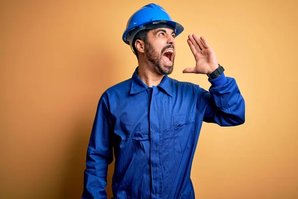 Mechaniker Mit Bart Blauer Uniform Und Schutzhelm Vor Gelbem Hintergrund — Stockfoto