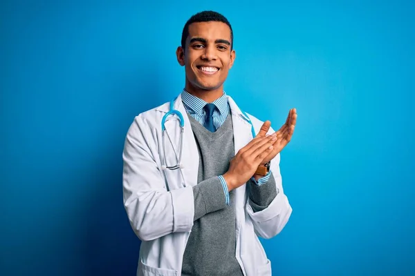 英俊的非洲裔美国医生 身穿外套 带着听诊器 站在蓝色的背景上 拍手喝彩 愉快地 快乐地 自豪地手挽手 — 图库照片