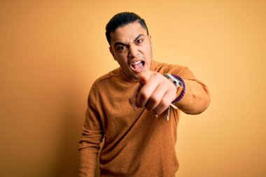 İzole edilmiş sarı arka planın başında dikilen Brezilyalı genç adam kameraya kızgın ve sinirli bir şekilde bakıyor.