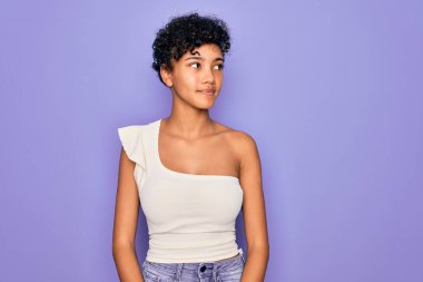 Güzel, Afro-Amerikan Afro-Amerikan bir kadın. Mor arka planda rahat bir tişört giyiyor. Gülümsüyor, yan tarafa bakıyor ve şöyle düşünüyor:.