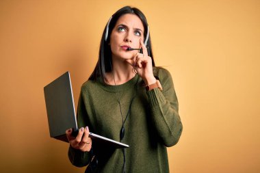 Çağrı merkezinde çalışan mavi gözlü genç bir operatör. Bilgisayar bilgisayarı ve kulaklık kullanıyor. Ciddi bir yüz ifadesi var.