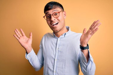 Sarı arka planda inek gözlüğü takan genç, yakışıklı İspanyol iş adamı çılgın ve başarıyı kollarını kaldırıp heyecanla haykırarak kutluyor. Kazanan konsept