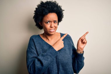 Kıvırcık saçlı, kıvırcık saçlı, genç, Afro-Amerikan bir kadın. Endişeli ve gergin bir kenara işaret ediyor. Endişeli ve şaşırmış bir ifadeyle.