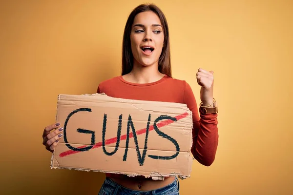 若い美しい活動家の女性は 銃のメッセージを指すと幸せな顔の笑顔で親指で側に表示されます停止バナーを保持 — ストック写真