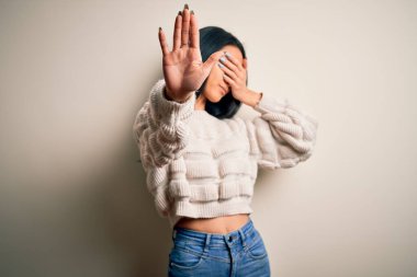 Genç, güzel Çinli bir kadın, izole edilmiş beyaz arka plan üzerine günlük süveter giyer, gözlerini ellerle kapatır ve üzgün ve korku ifadeleriyle jestleri durdurur. Utanç verici ve olumsuz bir kavram..