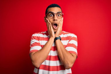 Genç, yakışıklı, Afro-Amerikalı, sıradan çizgili tişört ve gözlük takan, korkmuş ve şok olmuş, şaşırmış ve şaşırmış bir ifade takınıyor.