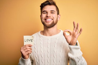 Sakallı, mavi gözlü, elinde aşk mesajı olan genç, sarışın romantik bir adam. Parmaklarıyla imza atıyor. Mükemmel bir sembol.