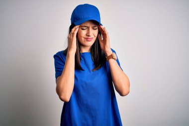 Mavi şapkalı genç teslimatçı kadın. Başı ağrıdığı için mavi arka planda duruyor. Migren ağrısı..