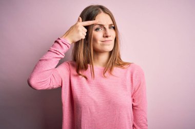 Genç, güzel, kızıl saçlı bir kadın pembe arka plan üzerine günlük süveter giyiyor. Alnındaki sivilceden mutsuz olduğunu gösteriyor. Siyah noktalı çirkin bir enfeksiyon. Sivilce ve deri problemi