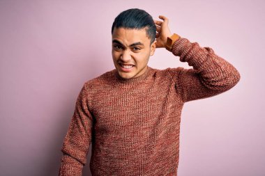 İzole edilmiş pembe arka planda duran sıradan süveter giyen genç Brezilyalı adam soru sormayı merak ediyor. Şüpheyle kararsız, kafa kafaya düşünerek. Düşünceli kavram.