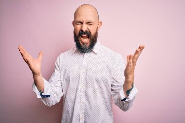 Kel, sakallı, zarif gömlekli, soyutlanmış pembe arka planda çılgın ve çılgın bir başarıyı kolları havada ve gözleri kapalı, heyecanlı bir şekilde kutlayan yakışıklı bir adam. Kazanan konsept