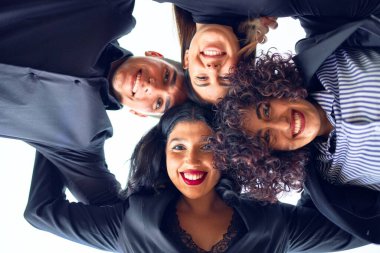 Bir grup iş adamı mutlu gülümsüyor. Kafa kafaya durmak, ofiste gülümseyerek sarılmak.