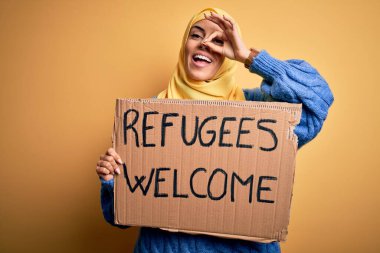 İslami başörtüsü takan güzel bir Arap kadın. Mültecilerle bayrak tutuyor. Mutlu yüzlü, gülümseyen bir mesaj.