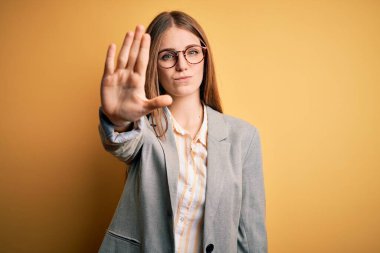 Sarı arka planda ceket ve gözlük takan güzel, kızıl saçlı kadın avucunun içi gibi şarkı söylemeyi kesiyor. Yüzünde olumsuz ve ciddi bir jest olan uyarı ifadesi.