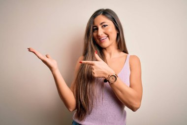 Uzun saçlı güzel esmer kadın izole edilmiş arka planda duruyordu. Kameraya hayret ediyor ve gülümsüyordu. Elle ve parmakla gösteriyordu..