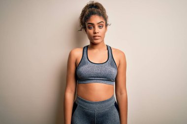 Genç Afrikalı Amerikalı sporcu kadın spor yapıyor beyaz arka planda spor giysisi giyiyor uykulu ve yorgun görünüyor, yorgunluktan yorgun ve akşamdan kalma, sabahları tembel gözler.