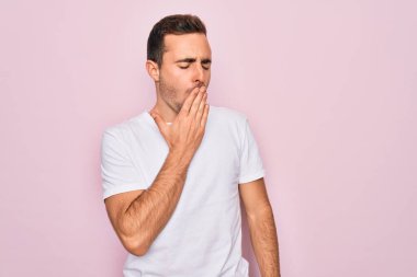 Pembe arka planda duran, mavi gözlü, sıradan beyaz tişörtlü yakışıklı adam esnemekten sıkılmış, ağzı eliyle kapatmaktan sıkılmış. Huzursuz ve uykulu..