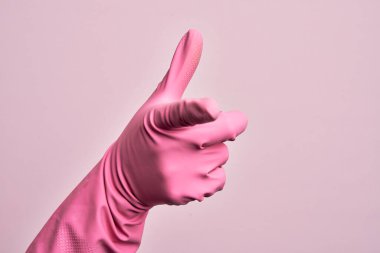 İzole edilmiş pembe arka planda temiz eldiveni olan beyaz bir gencin eli kameraya işaret ediyor ve yönü gösteriyor.