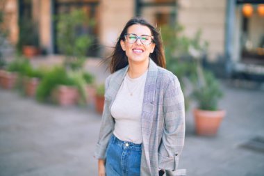 Mutlu ve kendinden emin gülümseyen genç ve güzel bir kadın. Kasaba caddesinde yüzünde gülümsemeyle dikilirken