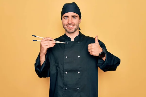 유니폼을 모자를 멋있는 요리사가 젓가락을 사용하여 행복하게 웃으며 미소를 손가락으로 — 스톡 사진
