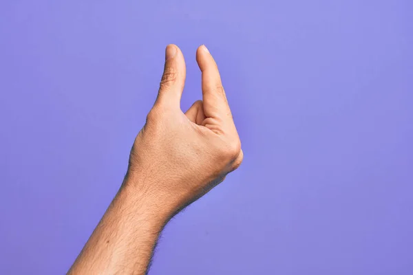 白人年轻人的手 用手指在孤立的紫色背景上伸出来 拿起看不见的东西 用手指握住能显示空间的物体 — 图库照片