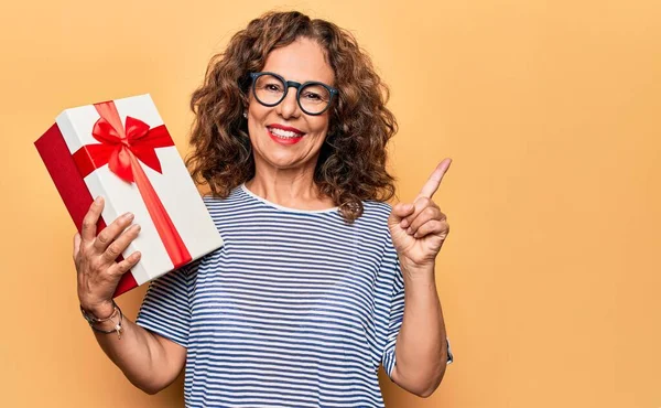 Mulher Bonita Meia Idade Segurando Presente Aniversário Sobre Fundo Amarelo — Fotografia de Stock