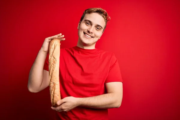 Young Handsome Redhead Man Holding Fresh Homemade Bread Isolated Red — Stock Photo, Image