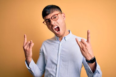 Sarı arka planda inek gözlüğü takan genç, yakışıklı İspanyol iş adamı elleri havada rock sembolü yaparken çılgın bir ifadeyle bağırıyor. Müzik yıldızı. Ağır konsept.