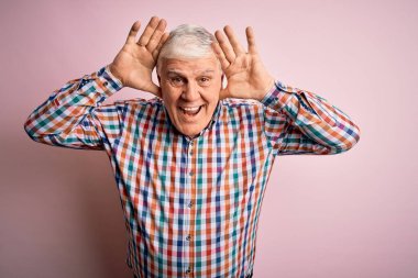 Üst düzey yakışıklı beyaz adam, pembe arka planda günlük bir tişört giyiyor. Gülümsüyor, gülümsüyor, elleri havada dikizliyormuş gibi yapıyor. Şaşırdım ve çıktım.