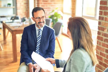 Mutlu ve kendinden emin gülümseyen iki orta yaşlı iş adamı. Ofisteki belgeleri okurken gülümseme ile birlikte çalışmak.