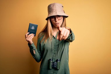 Sarışın, mavi gözlü, elinde Avustralyalı pasaportu olan, kamerayı işaret eden dürbünle gezen, sarışın bir turist. Ve sen, el işareti, ön taraftan pozitif ve kendinden emin bir jest.