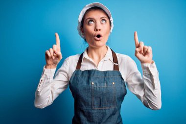 Mavi önlüklü, mavi şapkalı genç, güzel fırıncı kadın şaşkın ve şaşkın bir şekilde parmaklarıyla yukarı bakıyor ve kollarını kaldırıyordu..